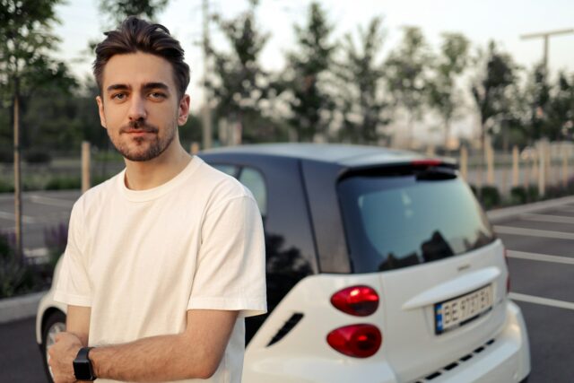 serious guy standing outside by car